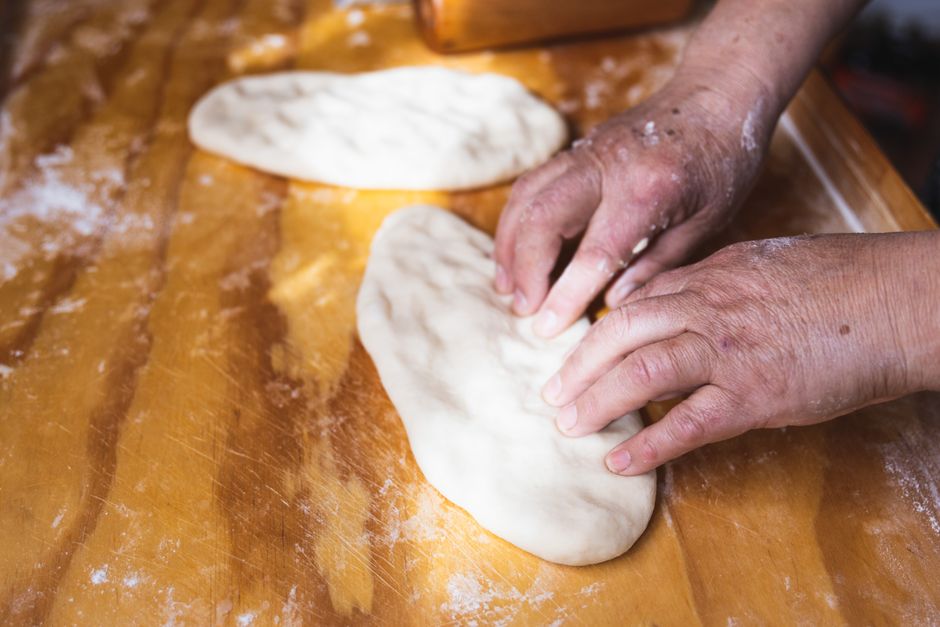 Close-up of hands kneading dough in preparation for baking on a wooden table.