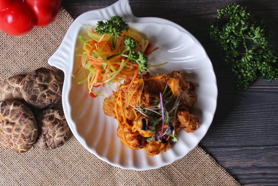 Delicious gourmet dish with crispy fried chicken and fresh vegetables on a stylish plate, exemplifying high cuisine.